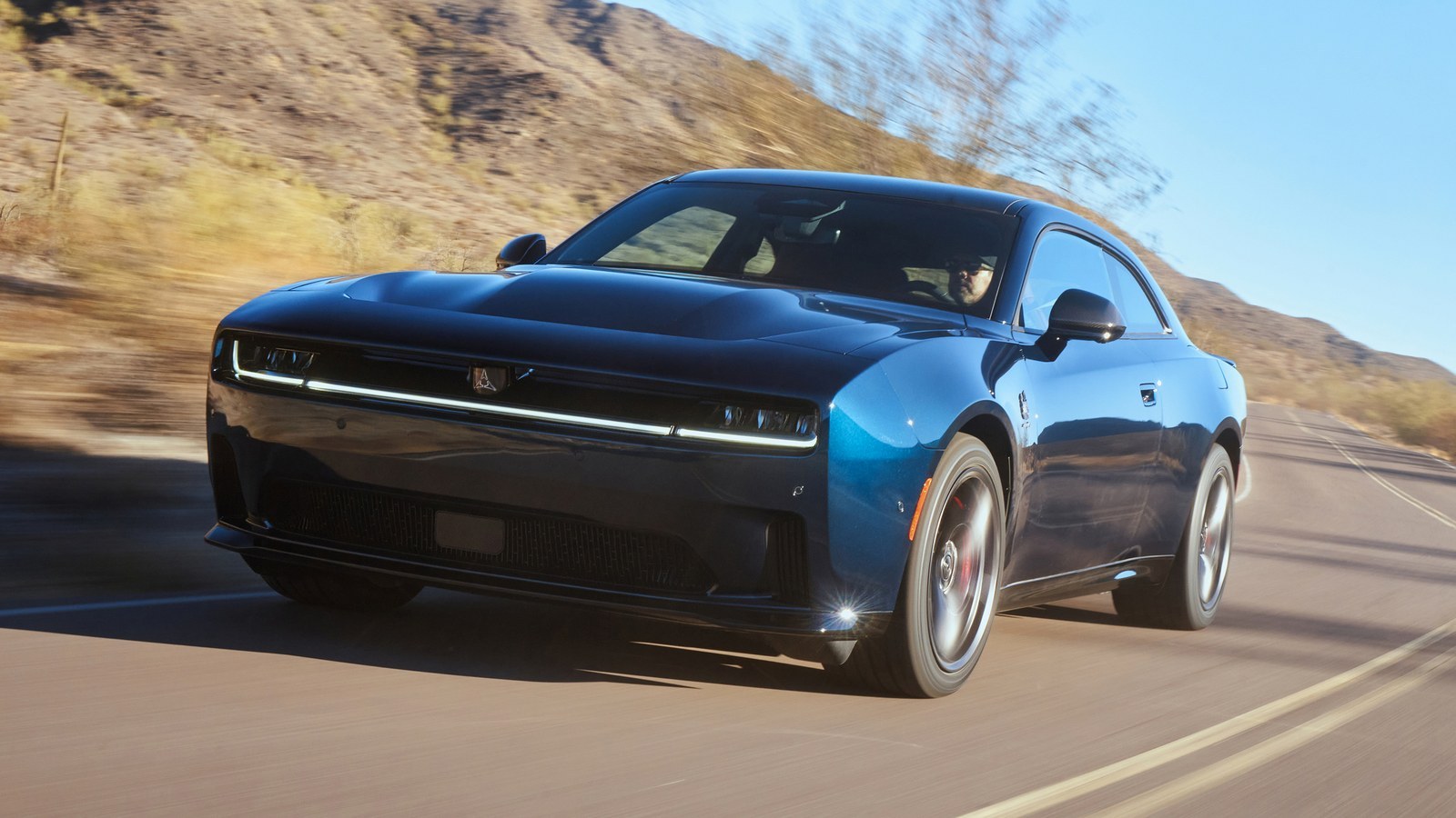 Blue Dodge Charger Daytona Scat Pack two-door electric muscle car driving on a desert road