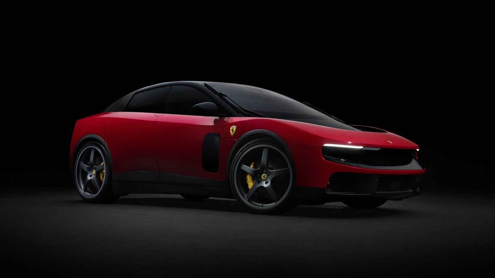 Red Ferrari Luce electric four-door in a dark studio, front three-quarter view with headlights on