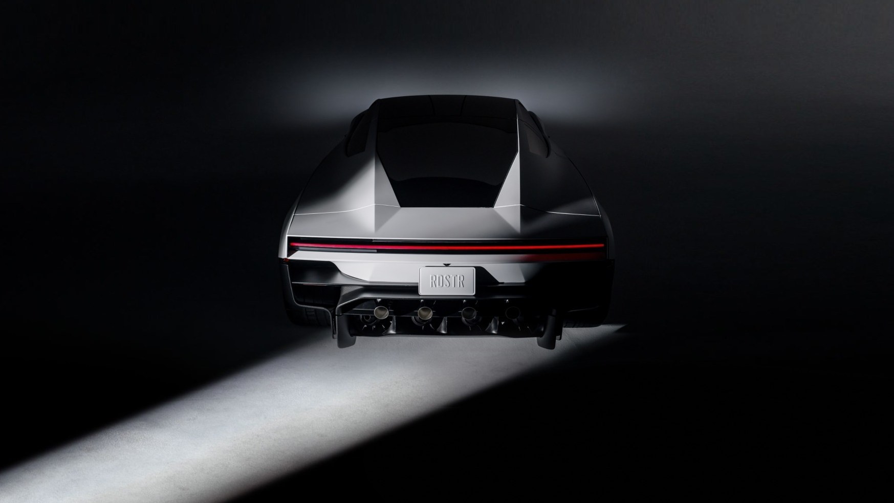 Rear view of the second-generation Tesla Roadster in a dark studio, with four nozzles below the rear bumper