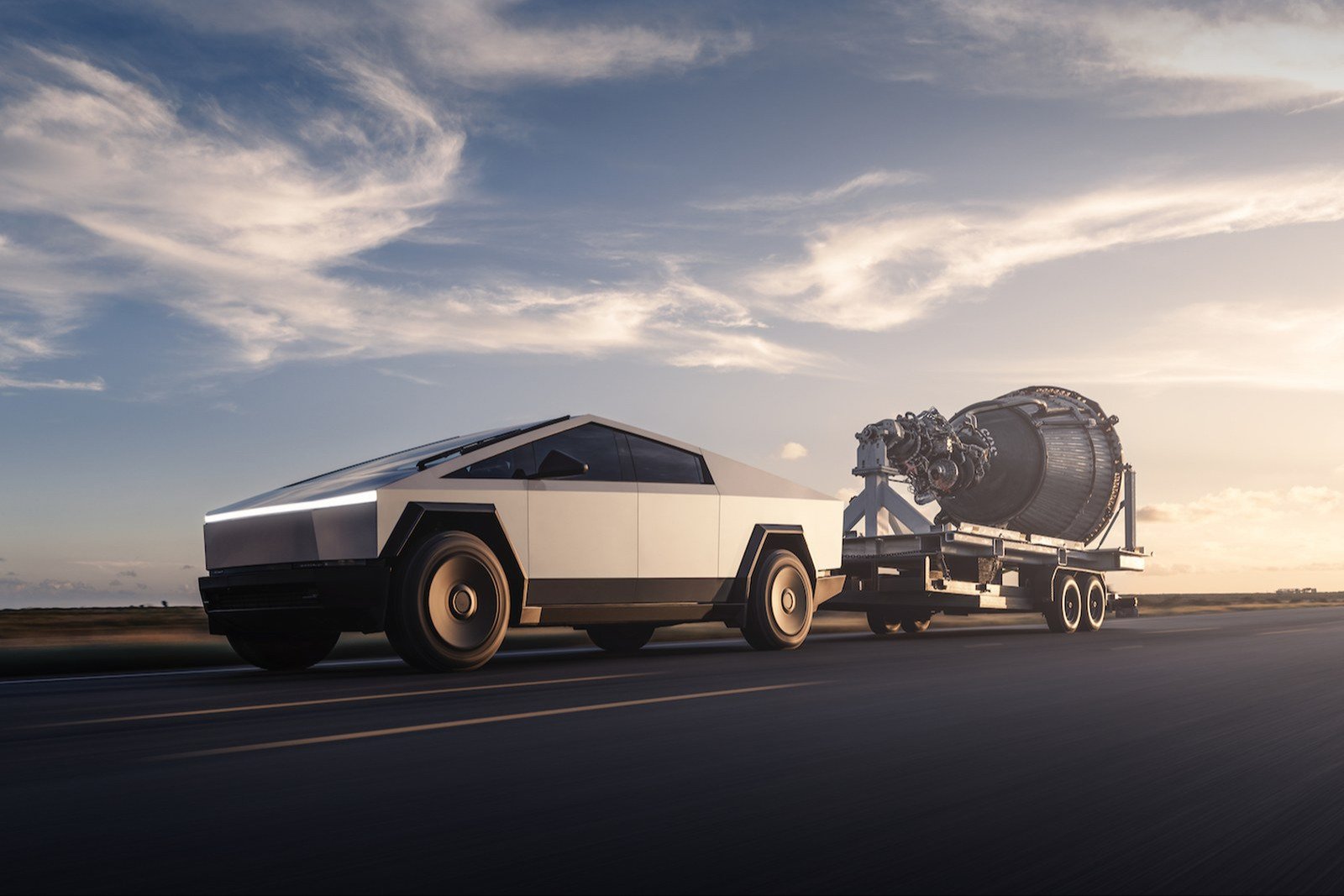 Tesla Cybertruck towing a rocket engine on a flatbed trailer along a Texas road at sunset