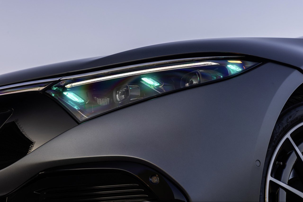 Close-up of a Mercedes-Benz headlight with turquoise automated driving marker lamps lit