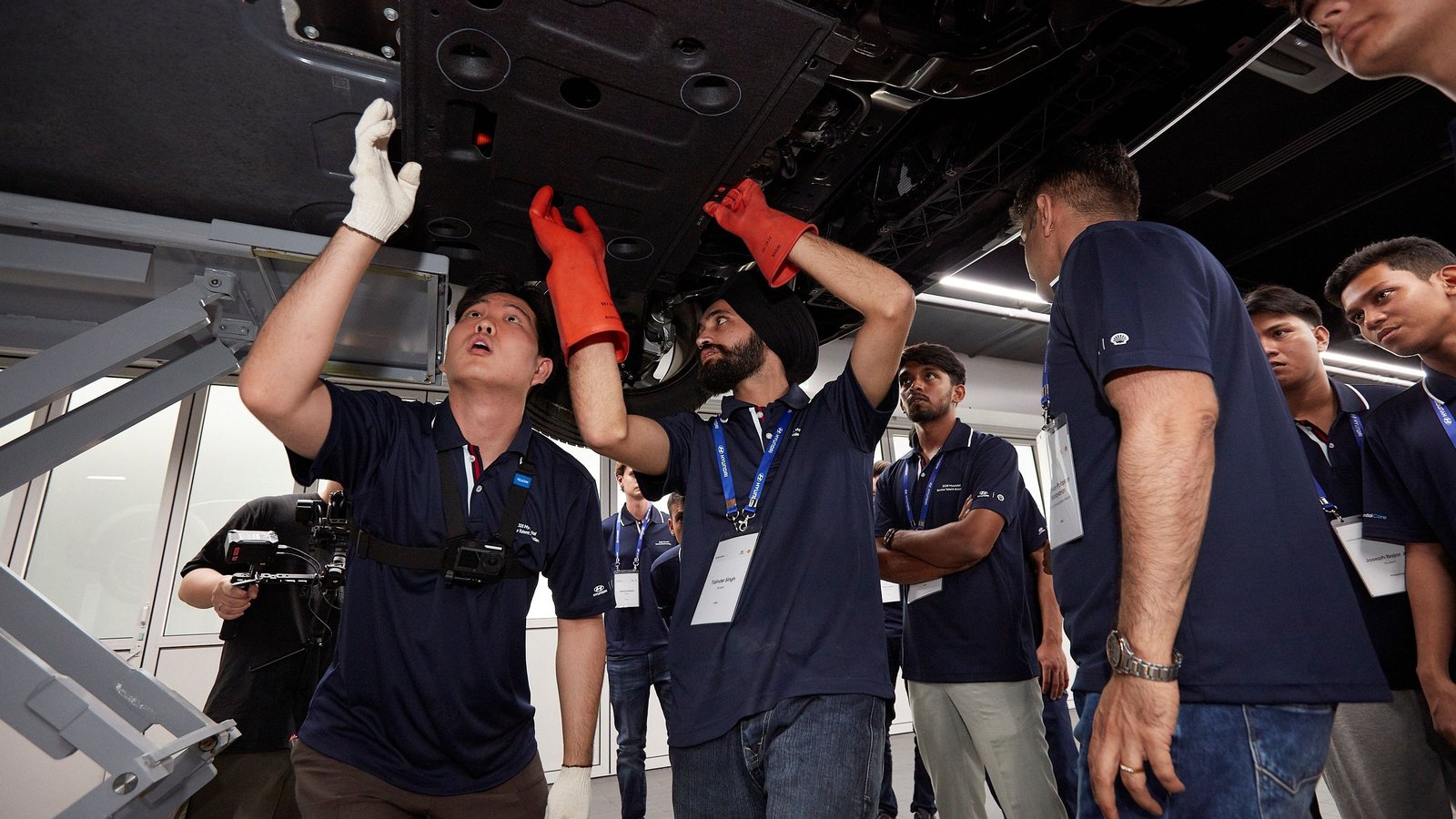 Technicians inspect the underbody of a car on a lift during Hyundai service training
