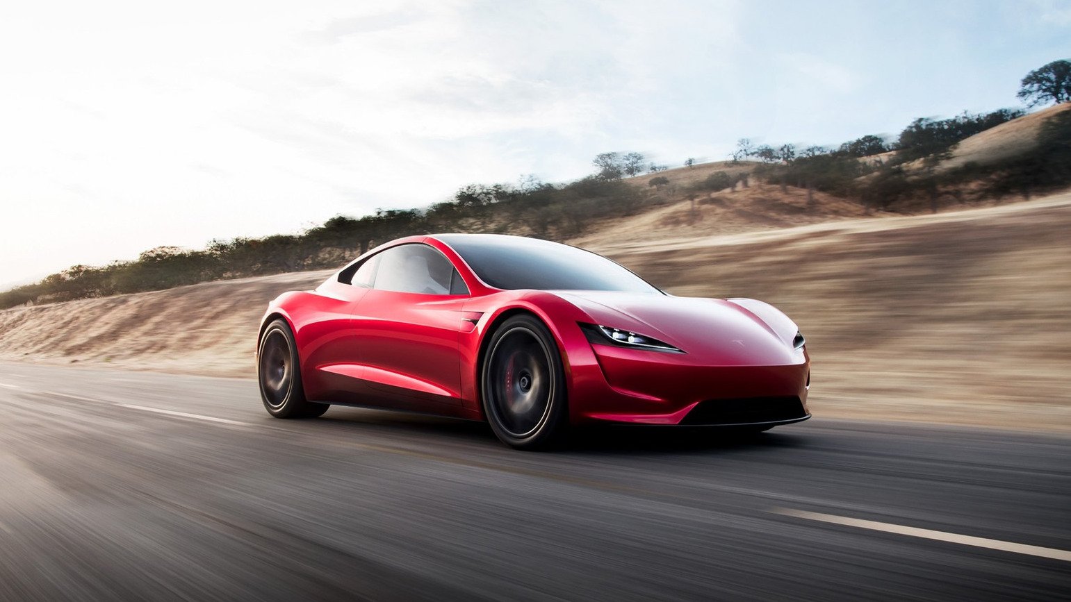 Red Tesla Roadster prototype shown in 2017, driving on a rural road