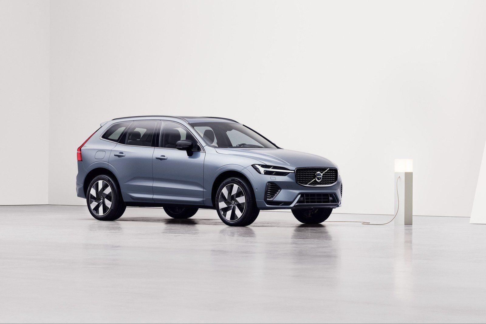 Volvo XC60 plug-in hybrid connected to a charger in a white studio
